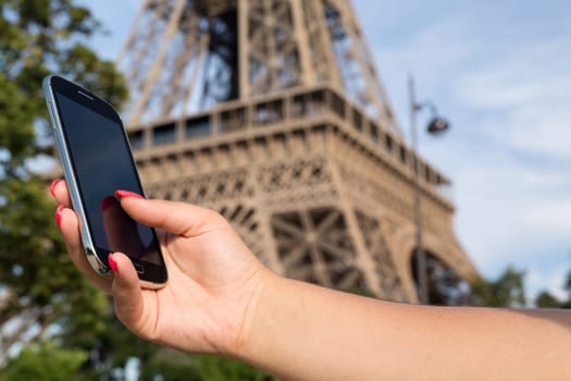 Woman consulting her smartphone with Eiffel Tower on background