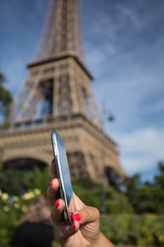 Woman consulting her smartphone with Eiffel Tower on background