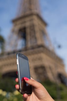 Woman consulting her smartphone with Eiffel Tower on background