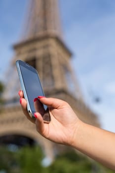 Woman consulting her smartphone with Eiffel Tower on background
