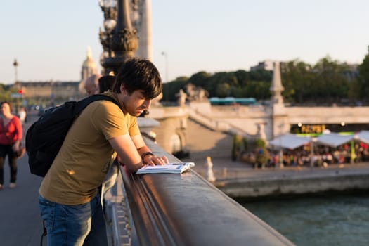 Young man on vacations in Paris, relaxing over the Alexander the 3rd bridge