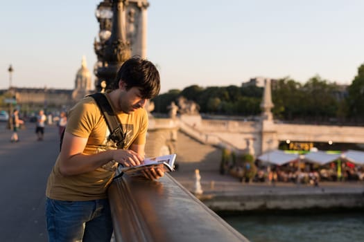 Young man on vacations in Paris, relaxing over the Alexander the 3rd bridge