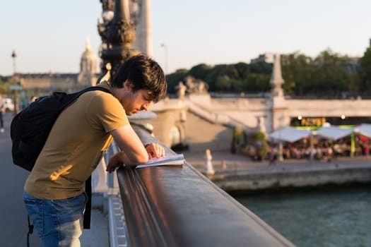 Young man on vacations in Paris, relaxing over the Alexander the 3rd bridge