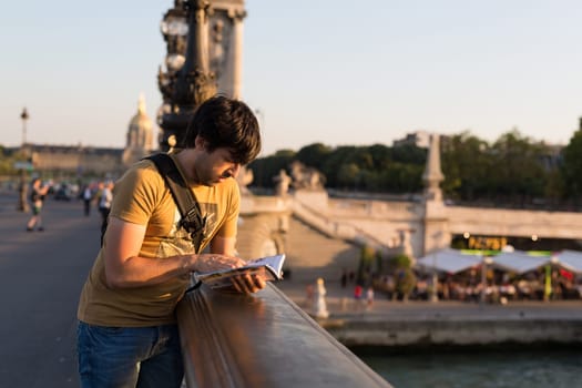 Young man on vacations in Paris, relaxing over the Alexander the 3rd bridge