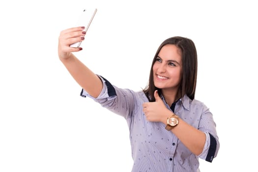 Happy young woman taking self portrait photography through smart phone over white background.