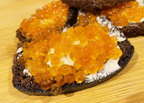 Red caviar on black bread with butter - photo