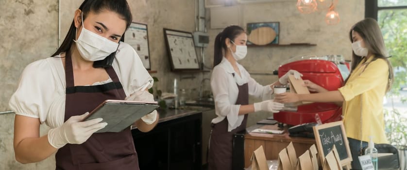 Panoramic Asian waitress take order from mobile phone for takeout or curbside pickup orders while city lockdown. They wear face mask to prevent from infection of coronavirus COVID-19 pandemic.