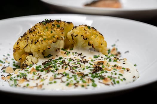 Roasted Cauliflower with Parmesan and Hazelnut topping with spring onion and cauliflower soup, gourmet international cuisine recipe. Restaurant gastronomy food and drink consumerism concept.