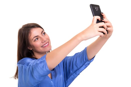 Happy young woman taking self portrait photography through smart phone over white background.