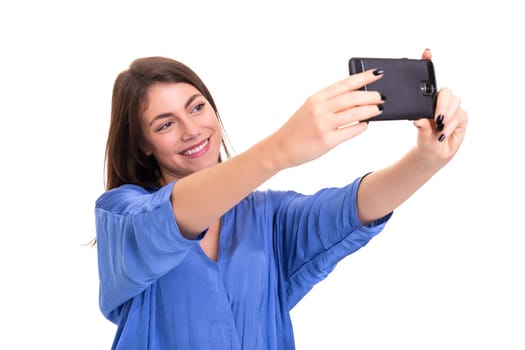 Happy young woman taking self portrait photography through smart phone over white background.