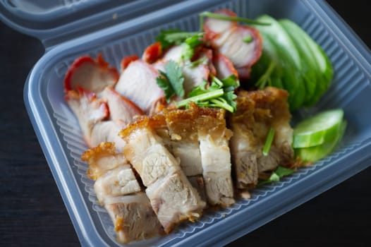 Barbecued red pork in sauce and crispy pork with rice in package .