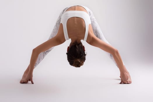 Sporty young woman doing yoga practice isolated on white background - concept of healthy life and natural balance between body and mental development