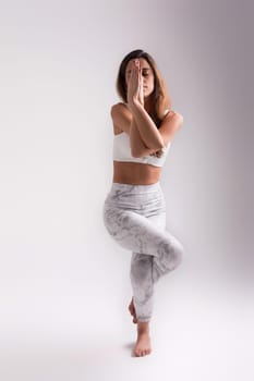 Sporty young woman doing yoga practice isolated on white background - concept of healthy life and natural balance between body and mental development