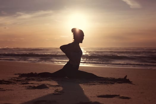 Sporty young woman doing yoga practice at the beach - concept of healthy life and natural balance between body and mental development