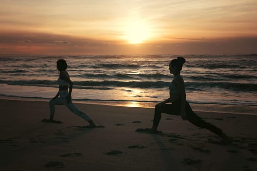 Sporty young women doing yoga practice at the beach - concept of healthy life and natural balance between body and mental development