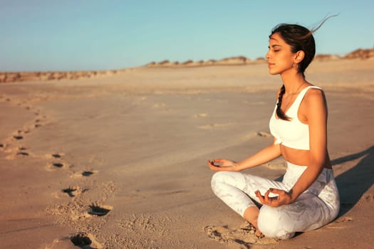 Sporty young woman doing yoga practice at the beach - concept of healthy life and natural balance between body and mental development