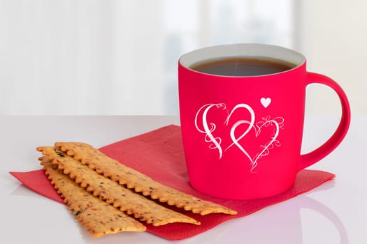 Valentines day background with red coffee mug with hearts and italian pastries for breakfast on table over blurred bright background. Concept morning coffee. Space.