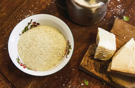 Grated cheese in a ceramic bowl on a rustic wooden board. Traditional Italian cuisine.
