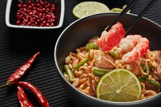 Pad Thai. Stir-fried rice noodles with chicken meat, shrimps,  scrambled egg, peanuts, vegetables and sauce in bowl. Thai food. Setting table.