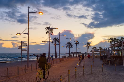 PAPHOS, CYPRUS - FEBRUARY 15, 2019: People walking by embankment at beautiful twilight in Paphos