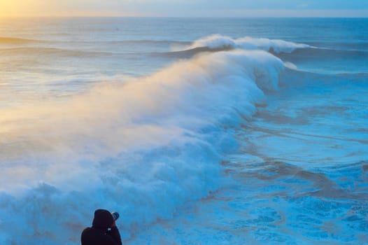 Photographer take picture of the ocean at sunset. Focus on the photographer. Nazare, Portugal