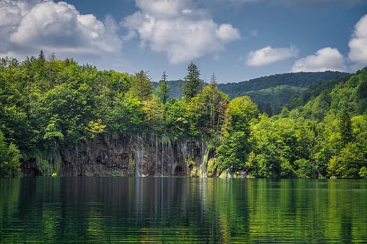 Beautiful waterfalls illuminated by sunlight and reflected in lake. Green lush forest, Plitvice Lakes National Park UNESCO World Heritage in Croatia