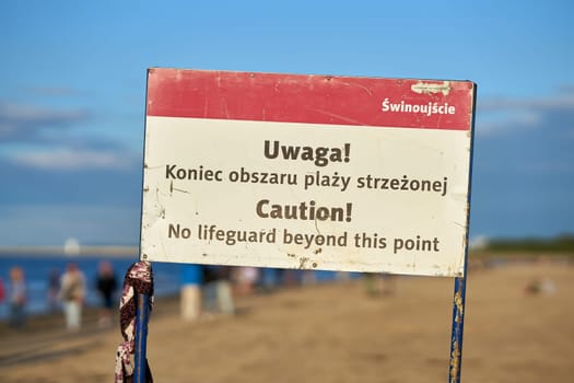 Sign on the beach of Swinoujscie on the Polish Baltic coast with the inscription "No lifeguard beyond this point"" in polish and english language"