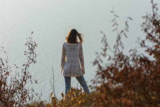 Slender girl standing on the seashore, rear view