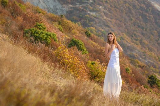 Beautiful slender girl in white clothes on the background of a beautiful mountain landscape