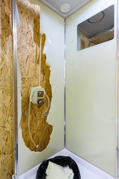 The back window of the shower stall is broken, and there's a bag of broken glass at the bottom