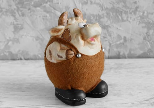 Clay bull figurine in black and white decorated with Christmas decorations on a white background. New year of the bull