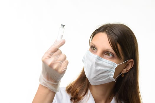 Girl doctor look at glass test tube with white powder, focus on girl