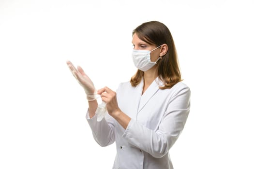 Girl doctor puts on transparent medical gloves on her hands