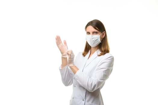 Girl doctor puts on transparent medical gloves on her hands, and looks into the frame