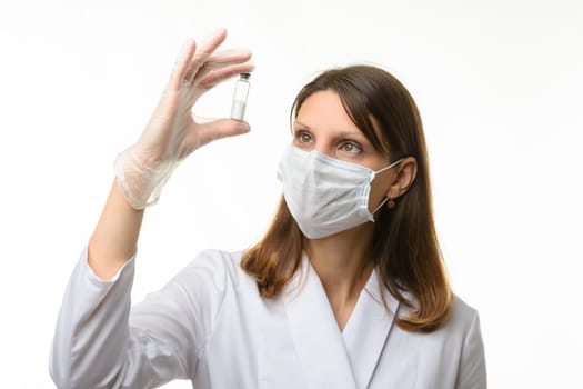 Doctor looks closely at the drug in a test tube, focusing on the doctor