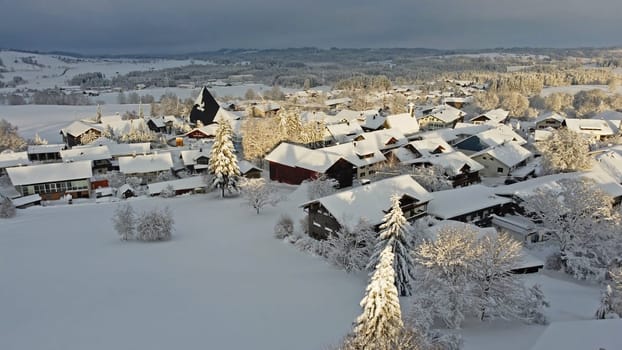 Aerial drone shot of a small town in Bavaria with snow in the evening sun