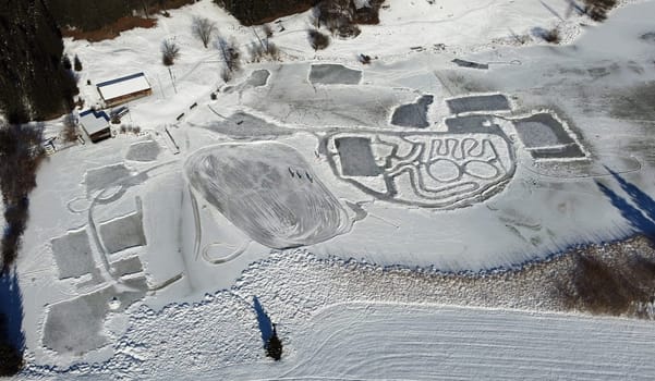 Aerial drone shot of frozen lake in winter with ice skaters
