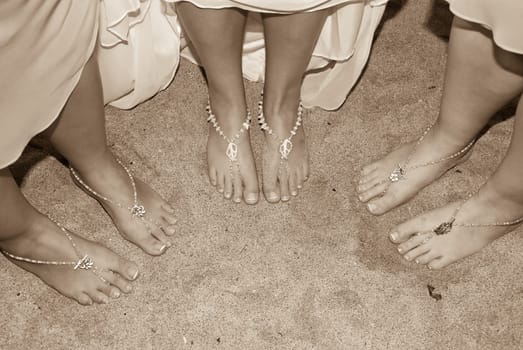 Three pair of feet wearing a jewel on the sand