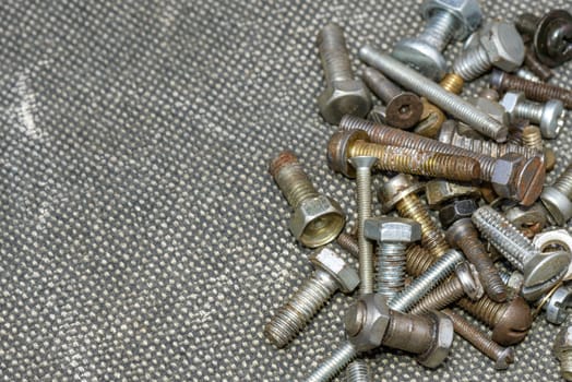 Several old screws on a grey texile background