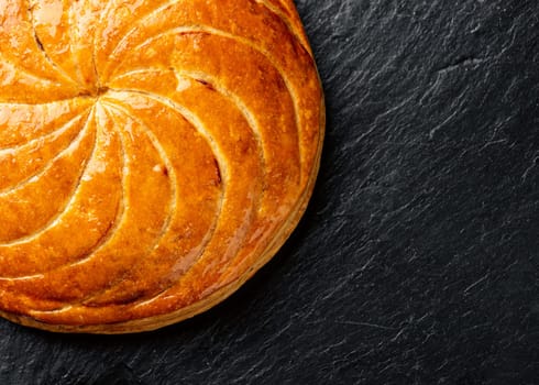Epiphany cake or galette des rois in French on black slate background