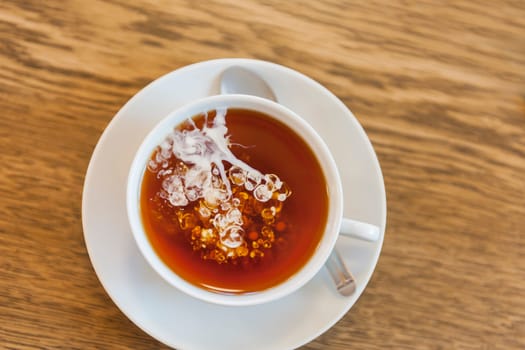 Top View Closeup of a white cup of tea with freshly poured cream spreading in a cloudy shape. This form of tea preparation became a tradition in northern Germany.