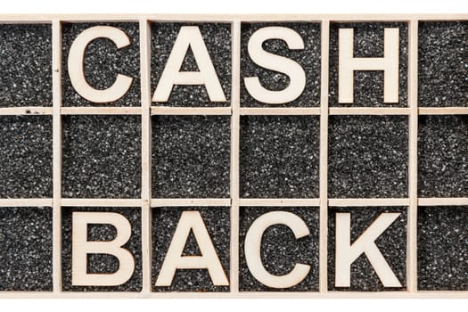 In einen Sammelkasten mit schwarzen Deko-Sand geordnete Sperrholz-Buchstaben die Wörter CASH BACK darstellend in Draufsicht auf weißen Hintergrund.