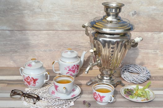 Tea party old samovar, cups and teapot on a summer day. Russian tradition.