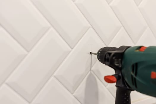 Drilling hole in ceramic tiles on the wall of bathroom. Close up view