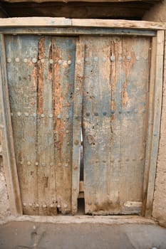 A closed,ancient,dilapidated wooden front door in the abandoned city of Al Hamra,Oman.