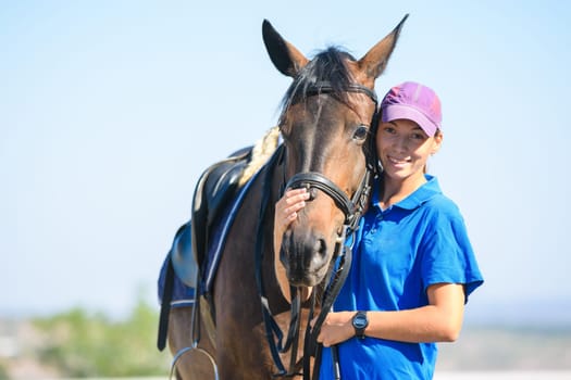 Portrait of a happy beautiful girl in casual clothes hugging a horse