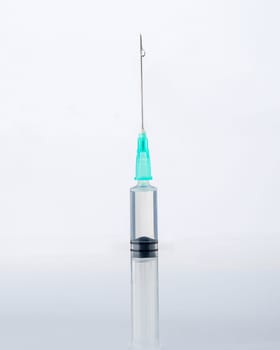 Close-up of a syringe and a drop of liquid on it, on a white background. Covid-19 vaccine concept.