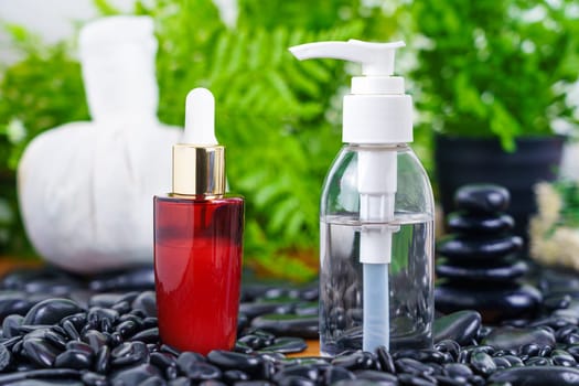 Thai Spa massage setting with red serum oil bottle dropper mock up or essential oil on black stone