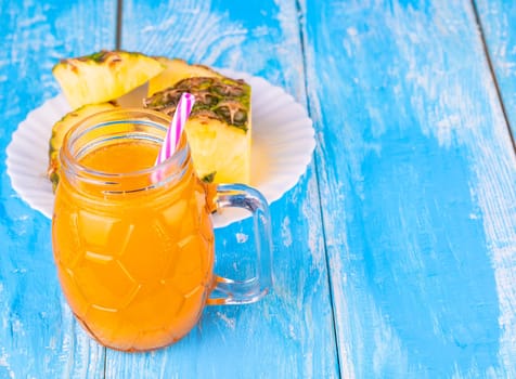 Pineapple and pineapple juice on the blue board background