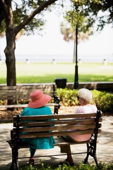 Rear view of two women sitting on a bench